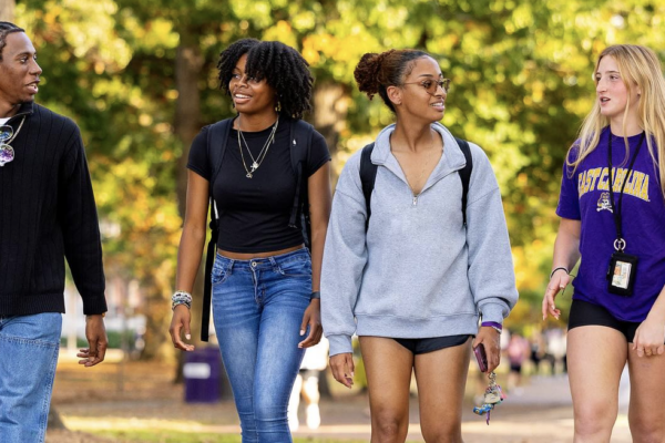 Four students walking side-by-side on the campus of East Carolina University